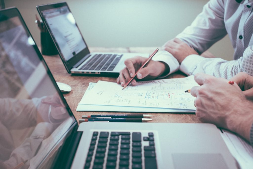 Business professionals reviewing risk data and contracts on a laptop, symbolizing ESG provisions in facilities management contracts and their impact on insurance underwriting.